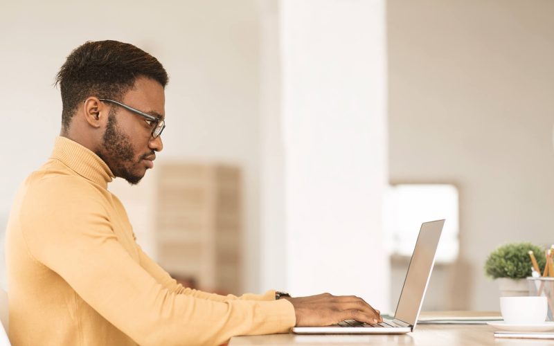 afro-guy-working-on-his-laptop-at-home-R5BG4EL